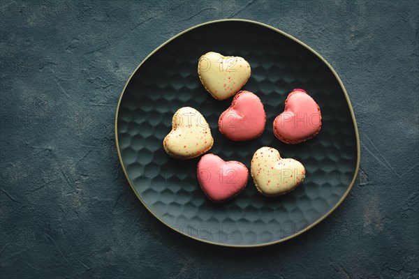 Macarons cakes in a shape of a heart. Small French cakes for Valentines Day. Sweet and colorful french macaroons.