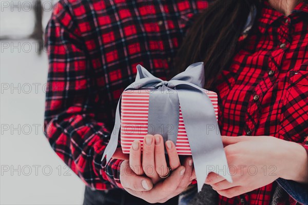 Boyfriend giving a gift box present with ribbon due to Saint Valentine day