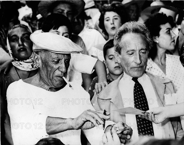 Artist Pablo Picasso sitting with Jean Cocteau at a bullfight