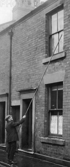 J Thompson the oldest knocker up in Blackburn. The job of a knocker-up's was to rouse sleeping people so they could get to work on time. They used a long and light stick (often bamboo) to tap on the bedroom windows. The knocker-up would not leave a client's window until they were assured the client had been awoken. In return the knocker-up would be paid a few pence a week by each of his clients for this service. 30th December 1911