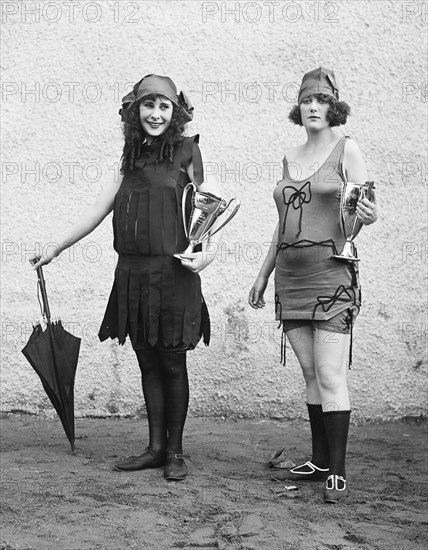 Women wearing bathing suits and holding trophy cups ca. 1922