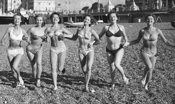 Friends ejoying the early spring sunshine on Brighton beach. Circa April 1952