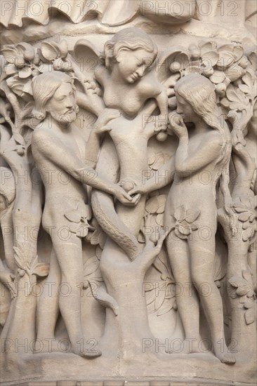 Adam and Eve. Detail of the main facade of the Notre-Dame Cathedral (Notre-Dame de Paris) in Paris, France. The damaged Gothic portal was restored by French architects Eugene Viollet-le-Duc and Jean-Baptiste Lassus in the 1840s.