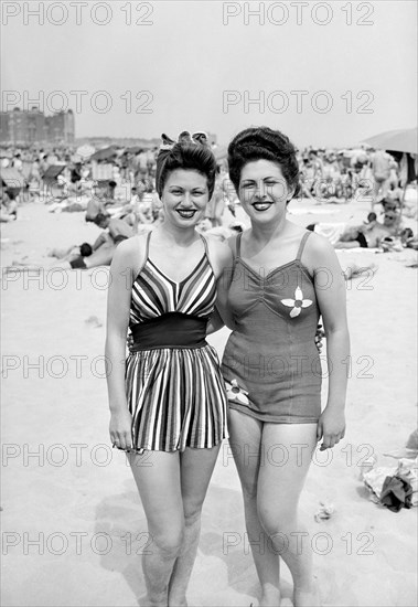 Sisters pose together on the beach in fashionable swimwear, ca. 1946.