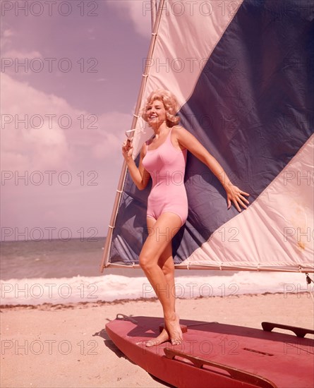 1960s BLOND WOMAN BEAUTY IN PINK SWIM WEAR BATHING SUIT POSED ON BLUE WHITE SAIL BOAT SAILFISH BOAT ON SUMMER SEASHORE BEACH - kg2693 SCH002 HARS WEAR LIFESTYLE OCEAN BEAUTIFUL SWIM GROWNUP ONE PERSON ONLY TRANSPORT UNITED STATES FULL-LENGTH PHYSICAL FITNESS GROWN-UP UNITED STATES OF AMERICA SAIL SURF CONFIDENCE TRANSPORTATION NOSTALGIA SUMMERTIME 20-25 YEARS FREEDOM TIME OFF HAPPINESS ADVENTURE LEISURE STYLES SUMMER SEASON RELAXATION GETAWAY RECREATION 18-19 YEARS HOLIDAYS FASHIONS MOBILITY SANDY VACATIONS BATHING SUIT SWIM WEAR FL PEOPLE ADULTS SEASHORE YOUNG ADULT WOMAN CAUCASIAN ETHNICITY