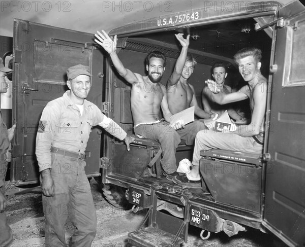 Jubilant, repatriated American prisoners of war wave happily as they await their departure by ambulance to a processing center on the first leg of their journey home. Panmunjom, Korea, Sept 4. 1953. U.S. Army