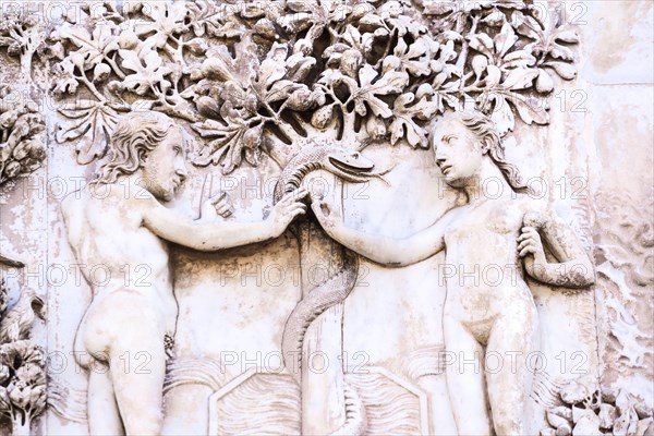 Detail of the facade of the Duomo of Orvieto, Italy. Marble bas-relief representing episodes of the bible.Adamo and Eva capture the apple instigated b