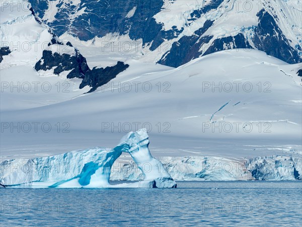 A huge iceberg arch in the Gerlache strait of the Antarctica peninsula as seen from an expedition ship