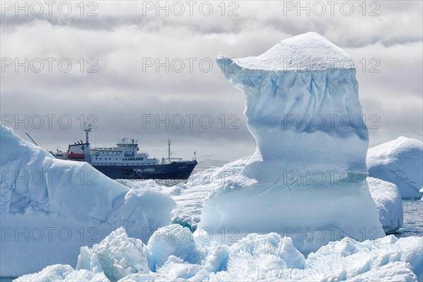 View between two snow peaks to a small cruise ship, Antarctic Peninsula, West Antarktika