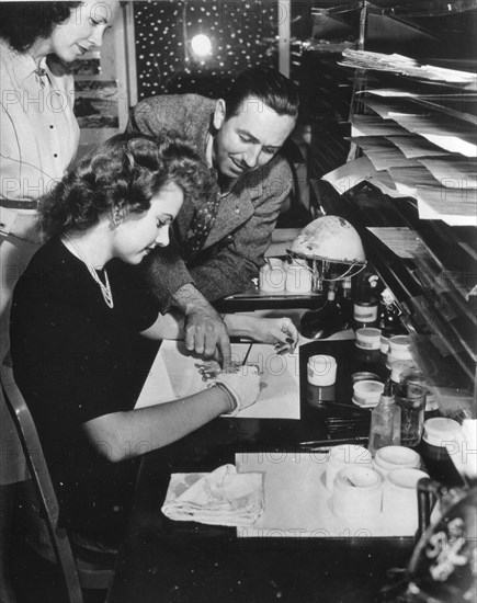 Walt Disney (right) gives painter Edith Moore advice on painting the finished celluloids which are photographed to make a Disney film, Burbank, CA, 1943. (Photo by Office of War Information/RBM Vintage Images)