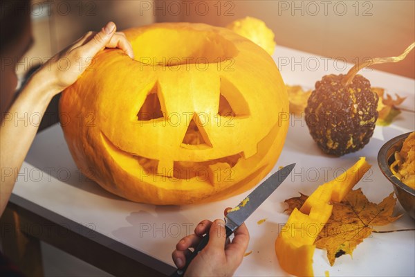 carving pumpkin into jack-o-lantern for halloween holiday decoration at home kitchen