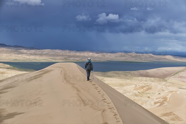 Tourist walking along the edge of the sand dune. Large barkhan in Mongolia sandy dune desert Mongol Els. Govi-Altay, Mongolia.