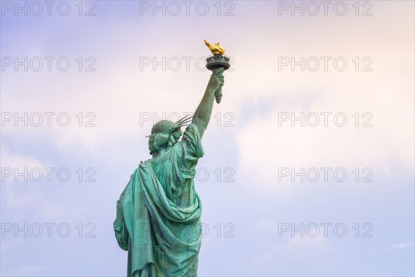 Close up image of the Statue of Liberty in New York seen from behind with cloudy blue sky