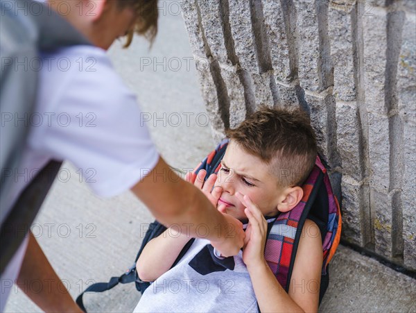 Cruel teenagers punching younger boy, physical intimidation, school bullying