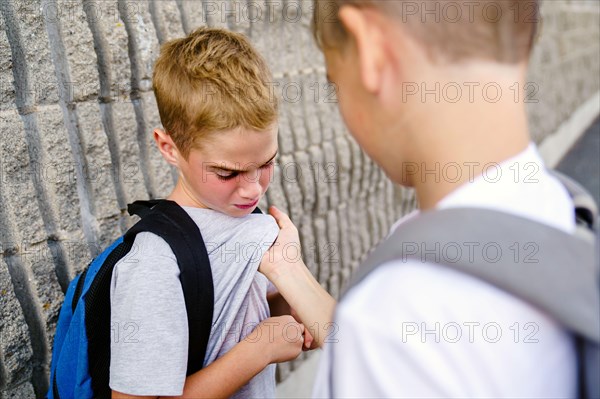 Cruel teenagers punching younger boy, physical intimidation, school bullying