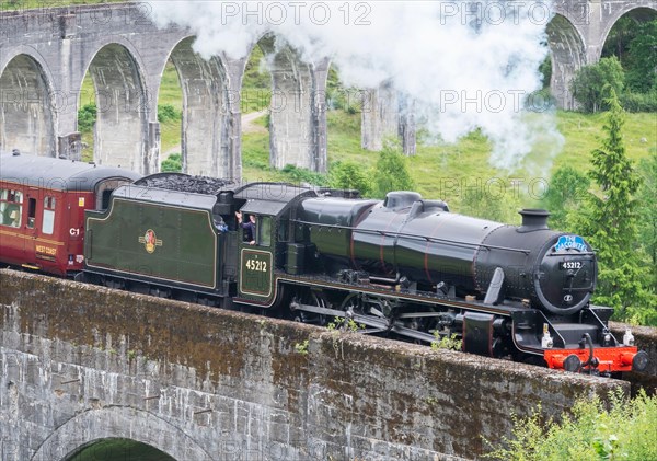 Glenfinnan,Inverness-shire,Scottish Highlands-July 21 2022:The train driver waves and lets off steam to onlookers,as the iconic train,shown in Harry P