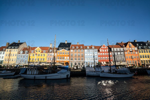 The colourful streets of Copenhagen, Denmark, along Nyhavn Quayside, on a sunny day with a blue sky.