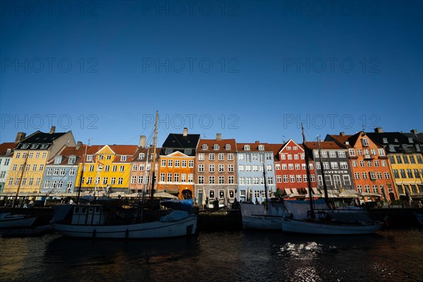 The colourful streets of Copenhagen, Denmark, along Nyhavn Quayside, on a sunny day with a blue sky.