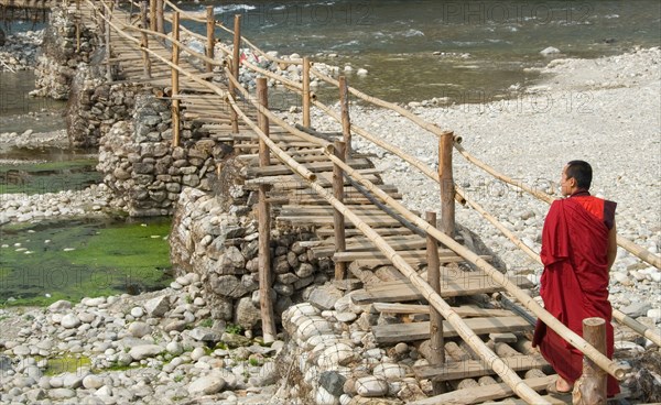 Monk walking to village from Punakha Dzong along temporary bamboo suspension bridge over Mo Chhu (Mother River), Bhutan