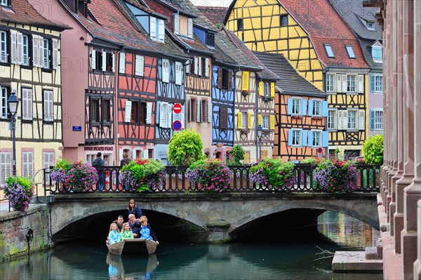 Tourists in boat at sightseeing trip along the colorful timber framed houses at Petite Venise / Little Venice, Colmar, France