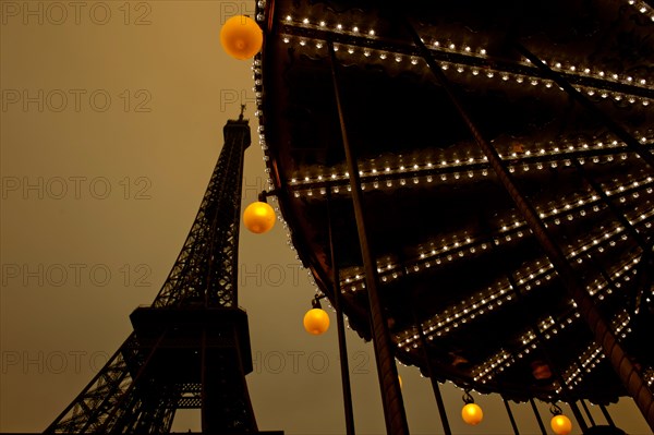 Evening at the Eiffel tour with carousel turning at the basement; Paris, France