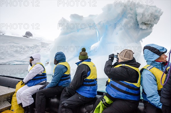 ANTARCTICA - A group of tourists cruise on the side of an inflatable boat past an a small iceberg in Curtis Bay, Antarctica.