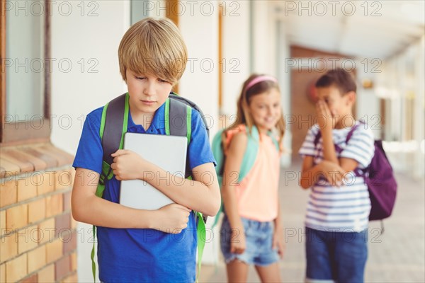 School friends bullying a sad boy in corridor