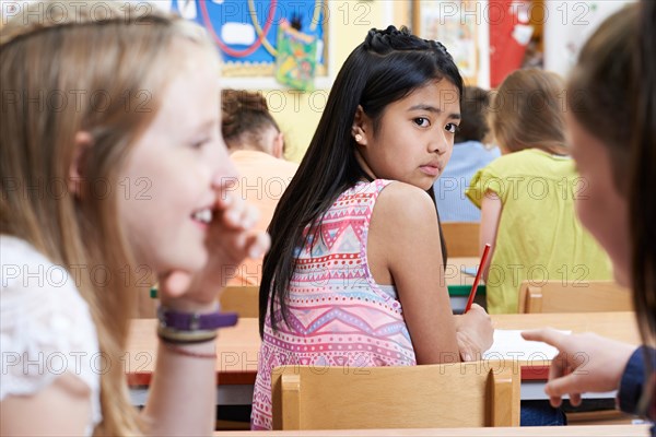 Unhappy Girl Being Gossiped About By School Friends In Classroom