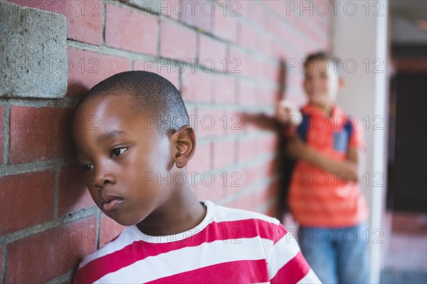 Schoolkid bullying a sad boy in corridor