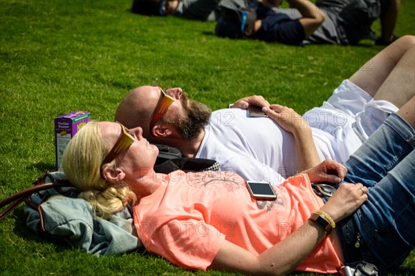 Nashville, Tennessee, USA. 21th August, 2017. A couple rests on the ground looking up at the sky in Centennial Park in Nashville, Tennessee, USA watching the solar eclipse that spanned a 70-mile wide stretch of the United States. Credit: Jim Diamond/Alamy Live News.