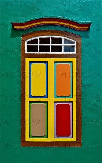 Traditional Indian window with colorful shutters in an orange wall of a shop house in Little India, Singapore.