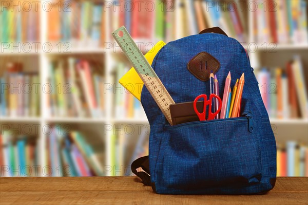 Composite image of bag with school supplies on wooden table