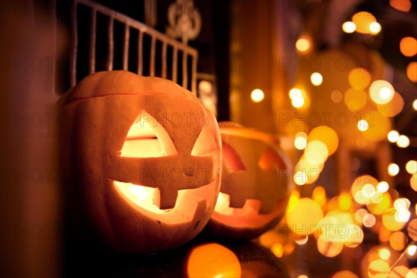 Halloween pumpkins at home on a fireplace with sparkling lights. Cosy autumn background.