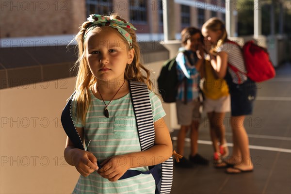 School friends bullying a sad girl in hallway of elementary school