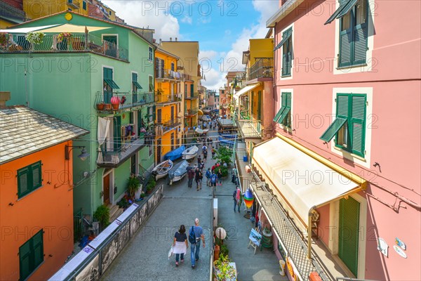 Tourists walk towards the sea at the colorful fishing village of Manarola, Italy, part of the Cinque Terre on the Ligurian Coast.