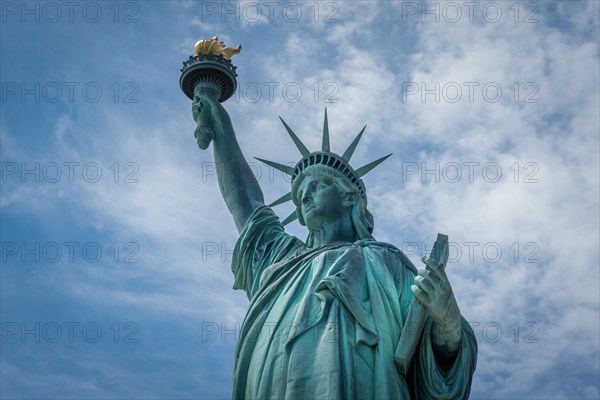 Shot of the Statue of Liberty in New York City, Usa. The shot is taken during a beautiful sunny day with a blue sky and white clouds in the background