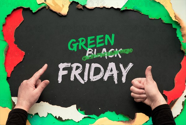 Green Friday, burnt frame with burned color paper. Hands showing OK sign and pointing index finger.Text "Black Friday Sale"  with word "Black" crossed