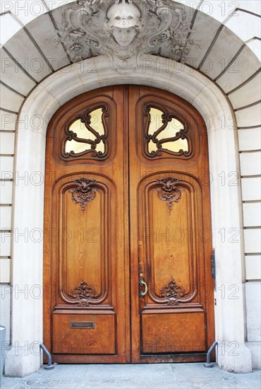 Old fashioned front door entrance, white facade and brown door, Paris, France