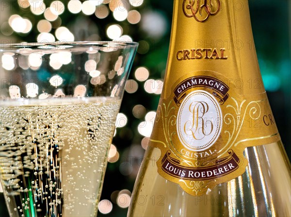 CRISTAL CHAMPAGNE Bottle and freshly poured glass of Louis Roederer Cristal luxury champagne with sparkling party celebration  lights in background