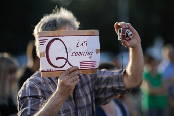 Bucharest / Romania - July 15, 2020: A man takes part at a protest and displays a Qanon message on a cardboard.