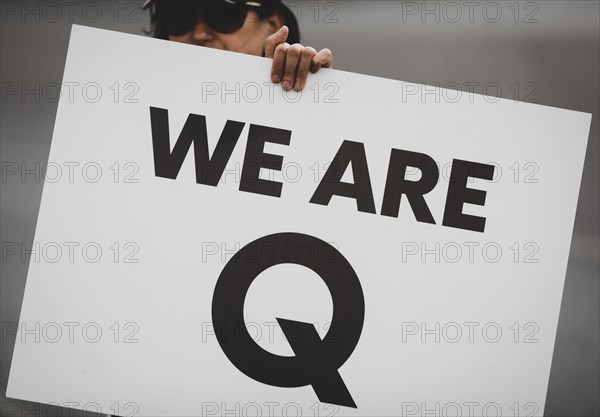 Bucharest, Romania - August 10, 2020: A woman takes part at a protest and displays a Qanon message on a cardboard.