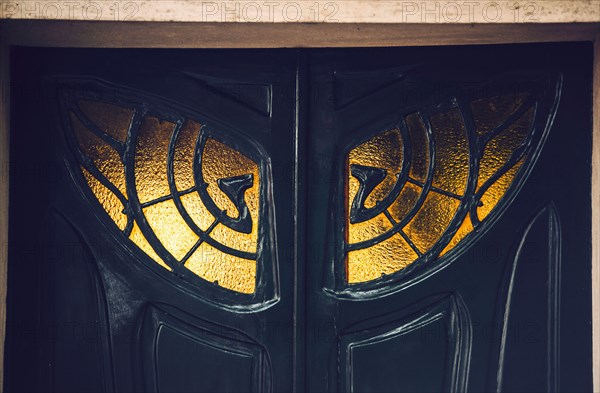 Close up view of black antique doors with ornamental window in Paris