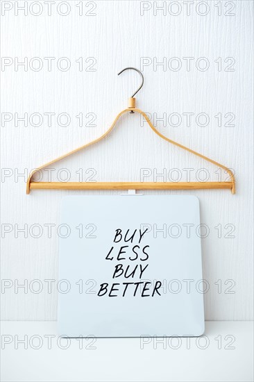 Sustainable consumption and production. Circular economy, Sustainable fashion concept with wooden clothes hangers and text Buy less, buy better