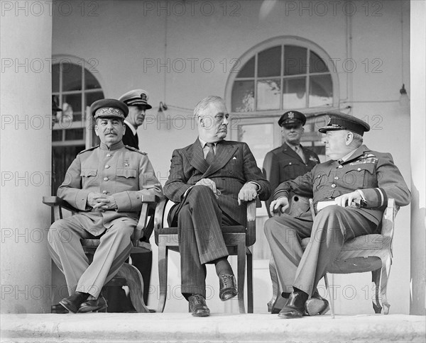 Joseph Stalin, Franklin D. Roosevelt and Winston Churchill on the veranda of the Soviet Legation in Teheran, during the first “Big Three” Conference, November 1943. In the background are aides to the US President.