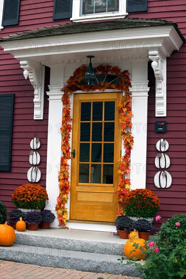 Front door of a traditional clapboard New England house, decorated for Halloween