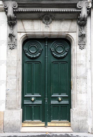 Dark green wooden door in old building facade. Paris, France
