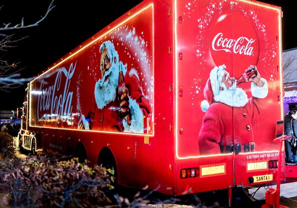 Coca-Cola Christmas truck at night in the UK depicting traditional Santa Claus or Father Christmas holding a bottle of Coke