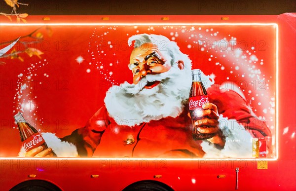 Coca-Cola Christmas truck side in the UK depicting traditional Santa Claus or Father Christmas holding a bottle of Coke