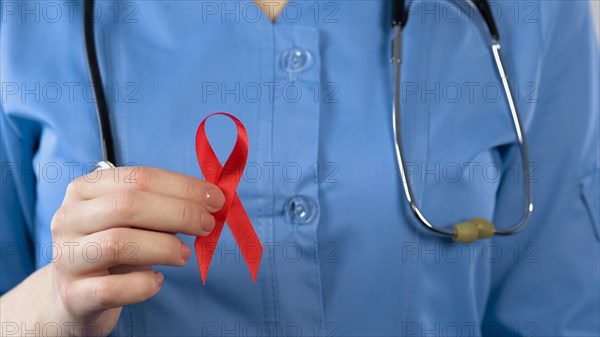 Female doctor showing red ribbon closeup, international AIDS awareness symbol
