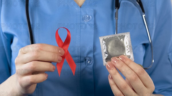 Doctor warning about AIDS disease showing red ribbon and condom, health campaign, stock footage